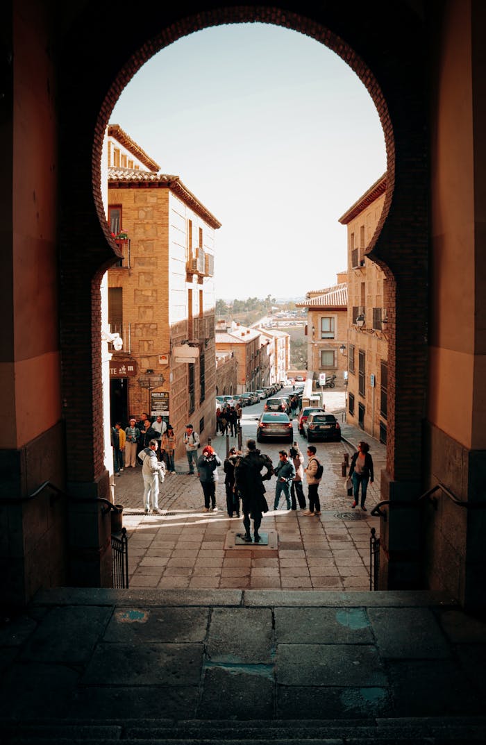 digital View through a medieval archway onto a bustling Spanish street in Toledo, Spain.