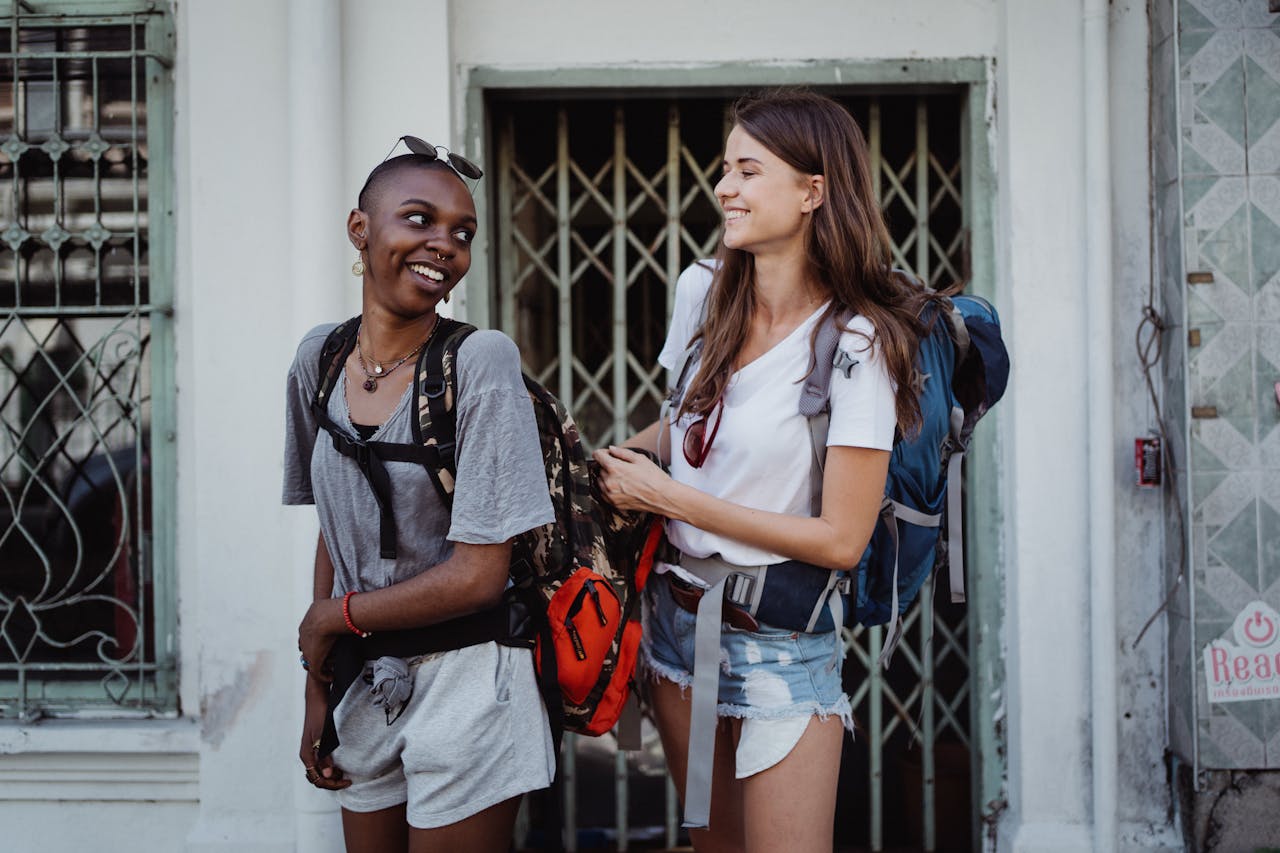 Services-01 Two young women backpacking and smiling in a lively urban setting, ideal for travel-focused content.
